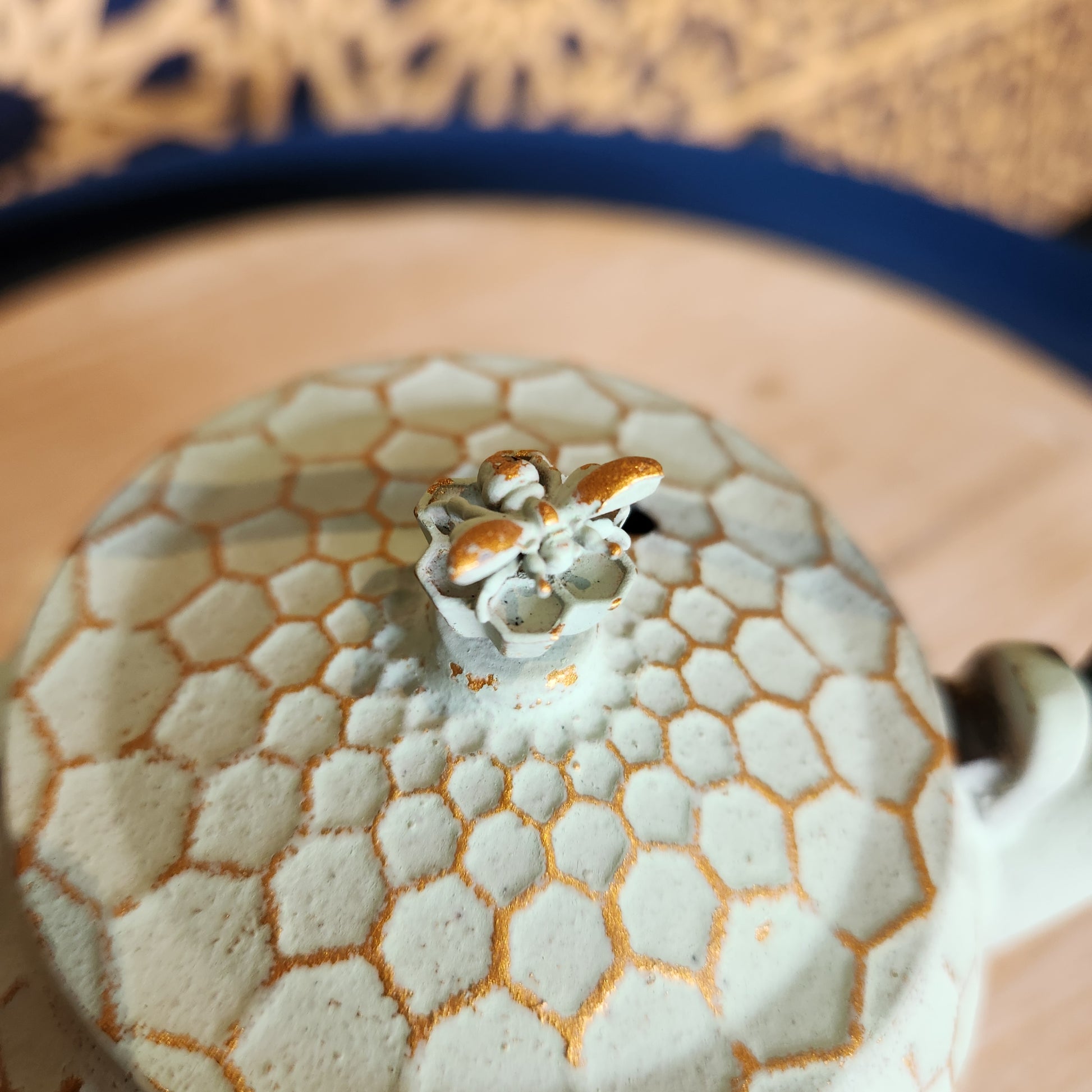 Close up of lid with a bee shaped handle on the honeycomb teapot